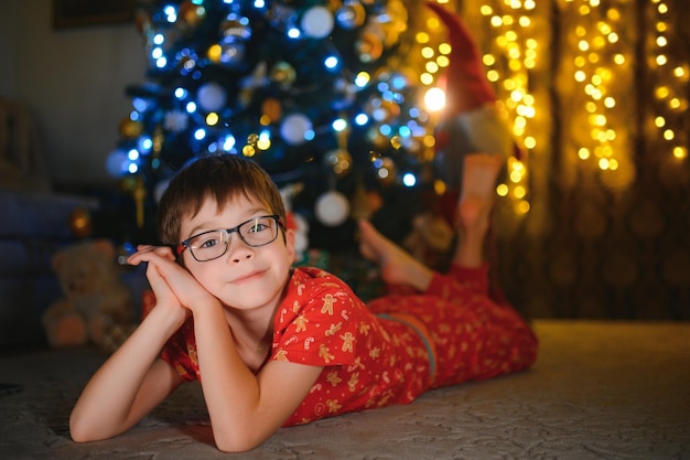 Bello ragazzino sorridente vicino all'albero di Natale