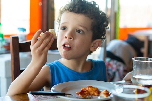 Bello ragazzo caucasico dai capelli ricci che mangia nel ristorante