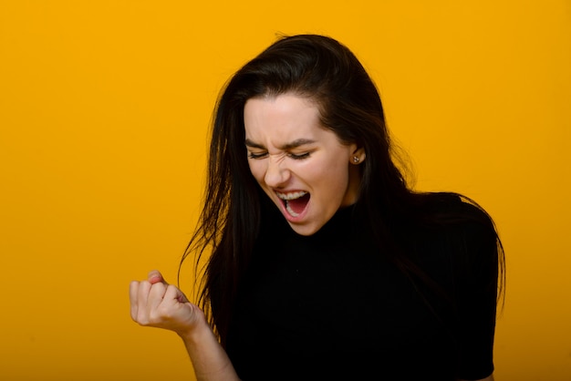 Bello ritratto anteriore femminile isolato sul backgroud giallo dello studio