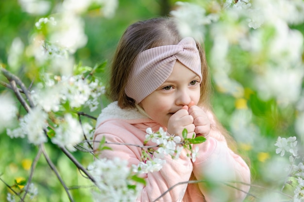 Bello ritratto della bambina vicino ad un ciliegio sbocciante