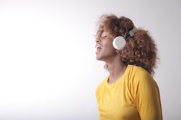 Bello scatto di una donna che ascolta musica con le cuffie isolate su sfondo bianco