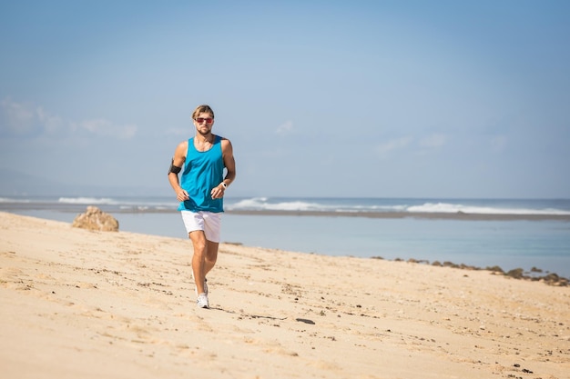 Bello sportivo che corre sulla riva del mare