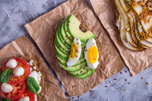 Bello spuntino sano - panini con pane di segale con avocado, mozzarella e pomodoro