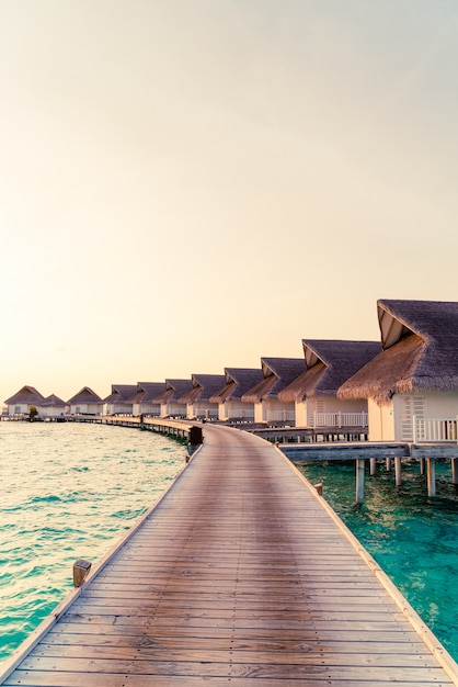 Bello tramonto tropicale sopra l'isola delle Maldive con il bungalow dell'acqua nella località di soggiorno dell'hotel