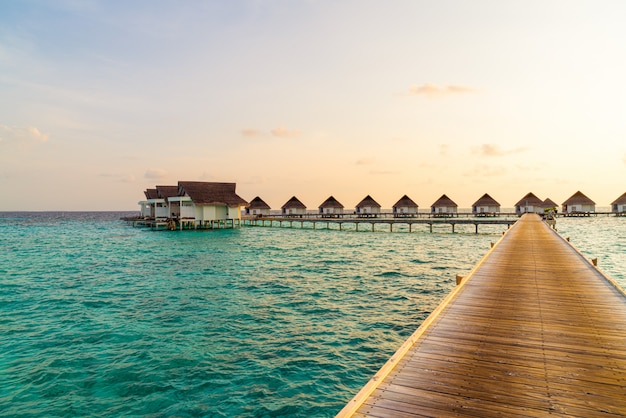 Bello tramonto tropicale sopra l'isola delle Maldive con il bungalow dell'acqua nella località di soggiorno dell'hotel