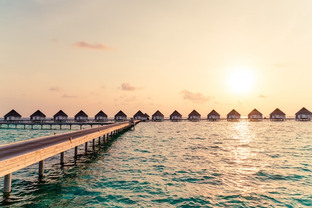 Bello tramonto tropicale sopra l'isola delle Maldive con il bungalow dell'acqua nella località di soggiorno dell'hotel