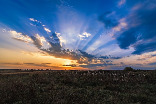 Bello tramonto variopinto con i raggi arancio del sole nel cielo blu la sera in autunno