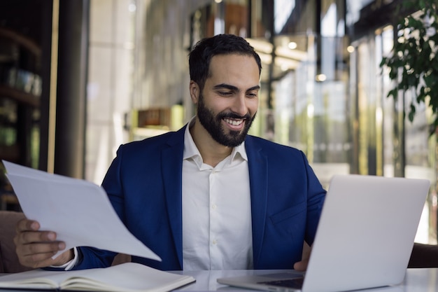 Bello uomo d'affari arabo che utilizza un computer portatile che pianifica il progetto di avvio che lavora online in ufficio