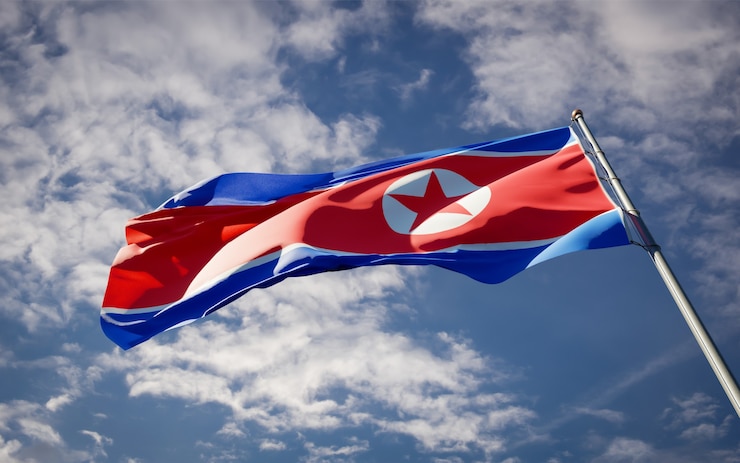Photo bendera negara nasional korea utara yang indah berkibar di langit biru