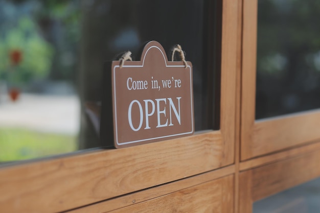Benvenuto Open barista cameriera donna che gira il cartello aperto sulla porta di vetro nella moderna caffetteria caffetteria pronta a servire bar ristorante negozio al dettaglio piccolo imprenditore cibo e bevande concetto