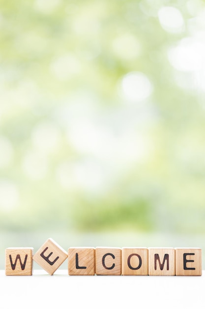 BENVENUTO parola è scritta su cubi di legno su uno sfondo verde estate Primo piano di elementi in legno