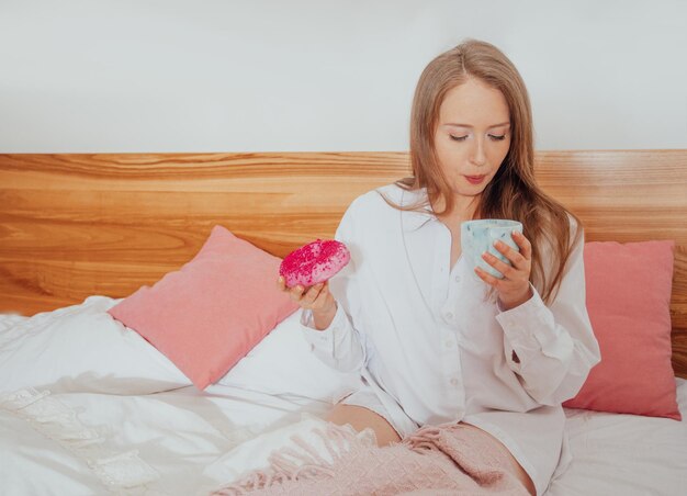 Bere caffè e mangiare una ciambella a colazione a letto