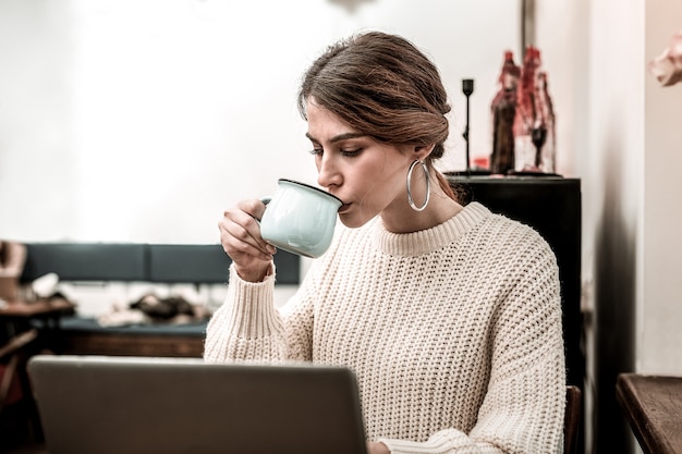 Bere caffè per rimanere energici Donna che beve un caffè mentre lavora a distanza