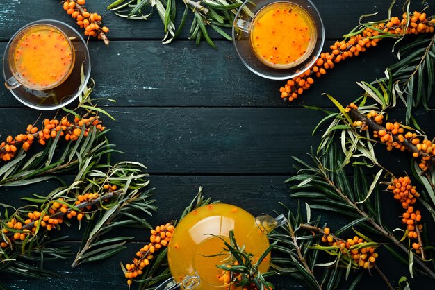 Bere dalle bacche di olivello spinoso Bevanda calda invernale Olivello spinoso fresco su un ramoscello Vista dall'alto Spazio libero per il testo