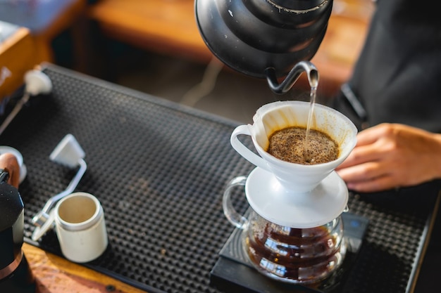 Bere la caffettiera è un caffè mattutino caldoUna mano che versa il caffè fumante in una tazza su una scrivania quando si lavora da casa
