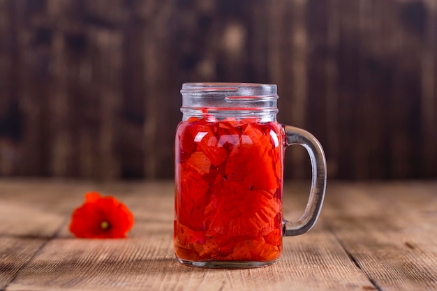 Bere tè al fiore di papavero rosso in una tazza di vetro su uno sfondo di legno da vicino concetto di alimentazione sana