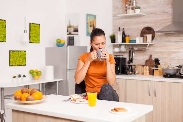 Bere un sorso di caffè al mattino gustando una deliziosa colazione