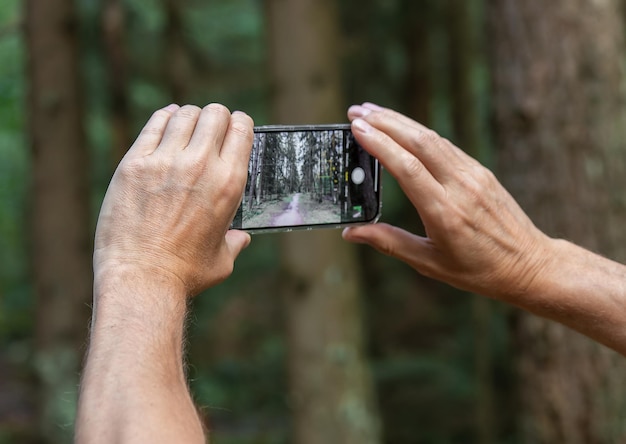 Berlino Germania 15 luglio 2023 Mani che tengono il telefono scattando foto della natura della foresta