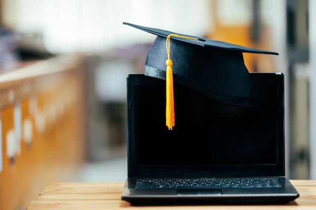 berretto da laurea nero con nappe gialle messo sul laptop