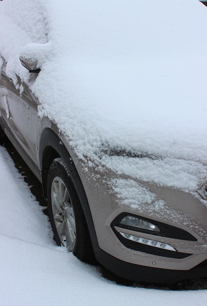 Berretto da neve su un cofano, parabrezza e specchietto laterale del veicolo parcheggiato su asfalto Foto Stock