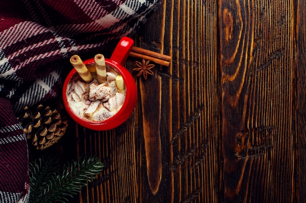 Bevanda al caffè invernale, cacao con panna montata e marshmallow in una tazza di ceramica rossa