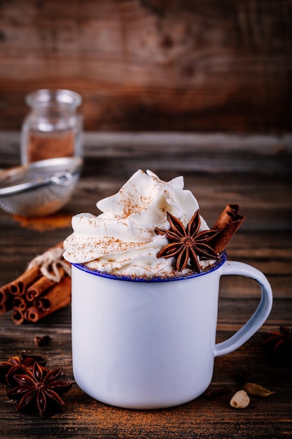 Bevanda al cioccolato caldo con cannella e panna montata su fondo di legno