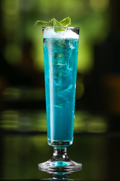 Bevanda alcolica cocktail blu su sfondo verde sfocato