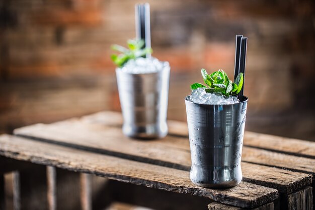 Bevanda alcolica cocktail Mint Julep su tavola di legno in pub o ristorante.