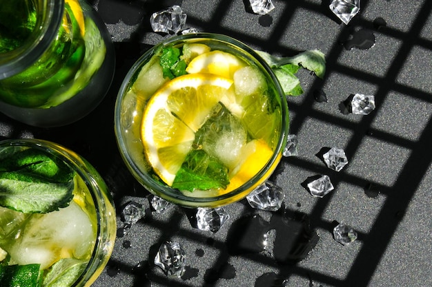 Bevanda alcolica cocktail rinfrescante Mojito Limonata con foglie di limone e menta su sfondo scuro Ombre alla moda Cubetti di ghiaccio Bevande disintossicanti rinfrescanti estive Concetto di stile di vita sano mangiare pulito Vista dall'alto