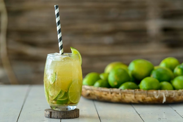 Bevanda brasiliana Caipirinha su un tavolo di legno bianco con limoni sullo sfondo