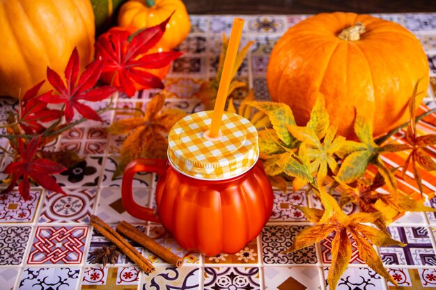 Bevanda calda autunnale con spezie di zucca, zucche con foglie autunnali vicine