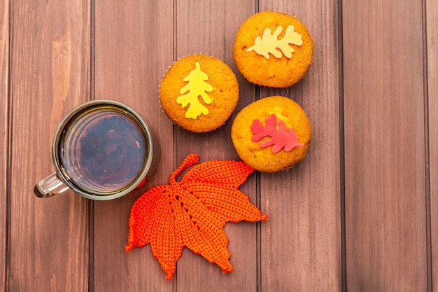 Bevanda calda d'autunno. Tè nero con cupcakes, foglie colorate