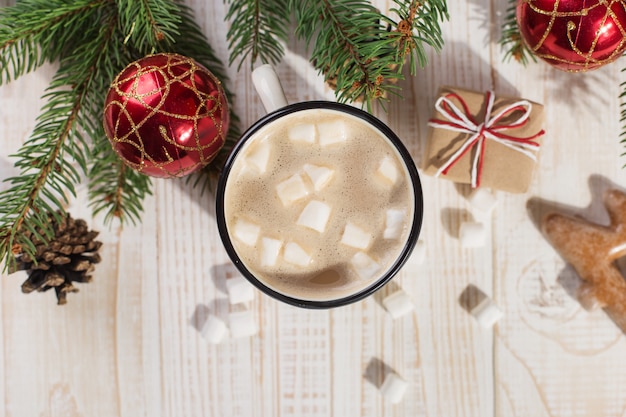 Bevanda calda di Natale con marshmallow in una tazza di ferro e biscotti di pan di zenzero, su un tavolo bianco. , vacanze, auguri copyspace.
