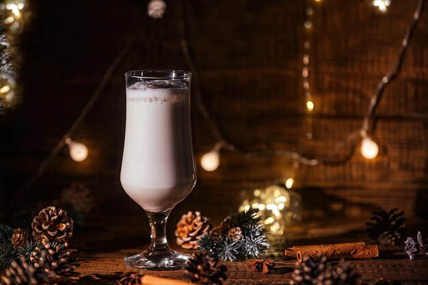 Bevanda calda di Natale. Zabaione alla cannella in vetro con rami di abete su sfondo scuro