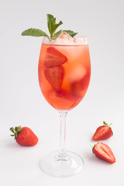 Bevanda cocktail con fragole e ghiaccio in un bicchiere su sfondo bianco. Posizione verticale. Avvicinamento.