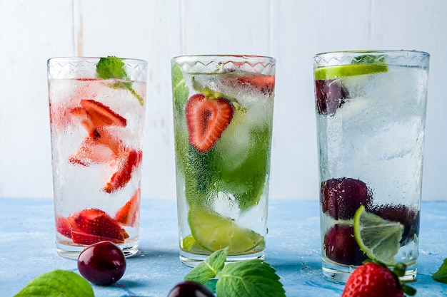 Bevanda Ddetox con fragola, lime, ciliegia e menta su un tavolo blu