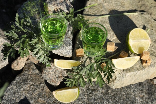 bevanda di assenzio verde sullo sfondo nero con zucchero e lime. Sfondo di pietre