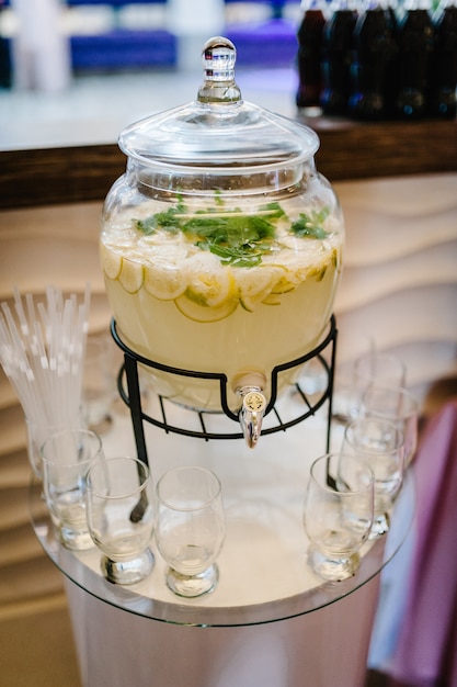 Bevanda di limonata di acqua gassata con ghiaccio, limone e foglie di menta in brocca su sfondo tavola rustica. Bicchieri Jar di fatti in casa.