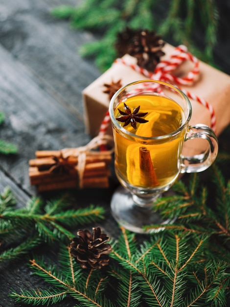 Bevanda di Natale grog con limone, cannella, vino sul tavolo di legno con scatole regalo per le vacanze