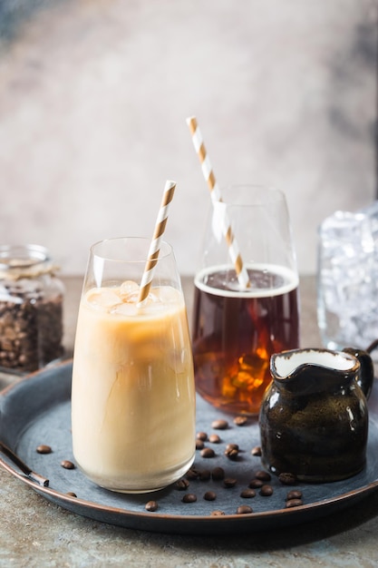 Bevanda estiva fredda di caffè freddo in un bicchiere alto e chicchi di caffè su uno sfondo di pietra.