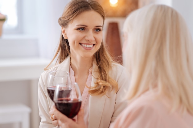 Bevanda femminile. Felice bella bella donna sorridente e guardando sua madre mentre beve vino con lei