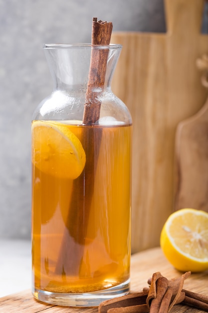 Bevanda fermentata con sidro o Kombucha. Bevanda fredda del tè con i batteri benefici, cannella, limone sulla vista laterale del fondo concreto con copyspace. Per un'alimentazione sana.