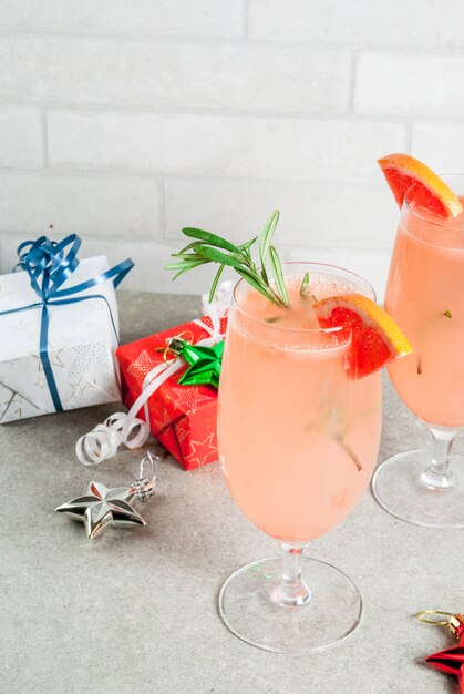 Bevanda festiva per la festa di Natale, cocktail Mimosa con champagne, pompelmo e rosmarino, su un racconto di pietra,