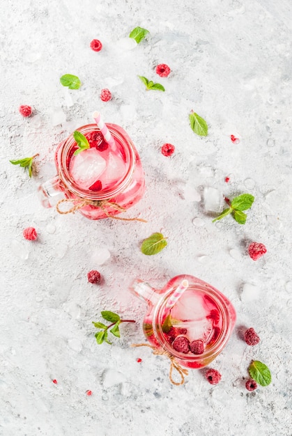 Bevanda fredda estiva, lampone sangria, limonata o mojito con lampone fresco e sciroppo, foglie di menta, su pietra grigia copyspace vista dall'alto