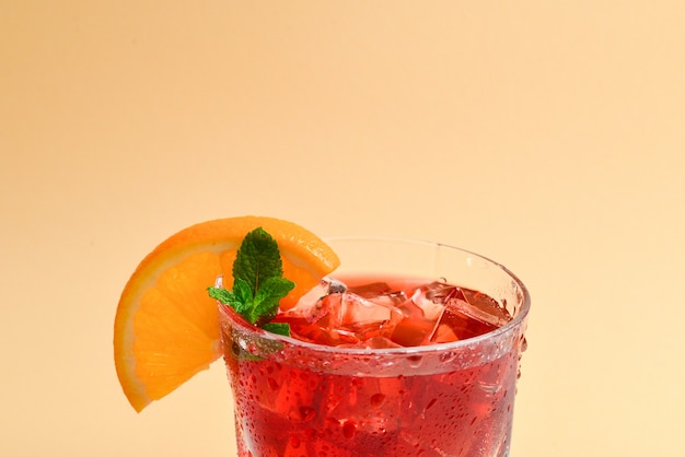 Bevanda fresca rossa con ghiaccio, pompelmo e menta su una priorità bassa beige. Spazio per testo o design.