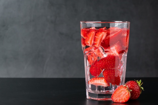 Bevanda ghiacciata con fragole su sfondo nero. Limonata estiva ai frutti di bosco. Posto per il testo.