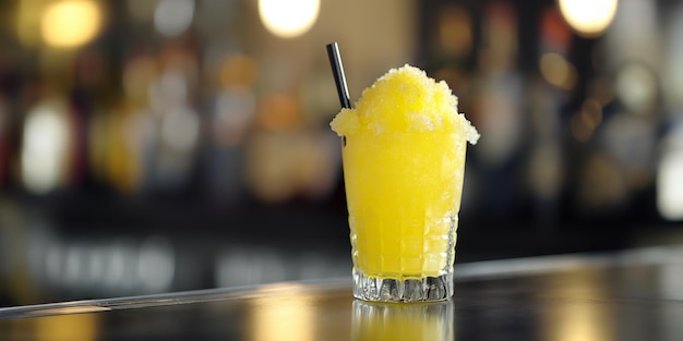 Bevanda gialla al mango e al limone con una cannuccia su un bancone del bar