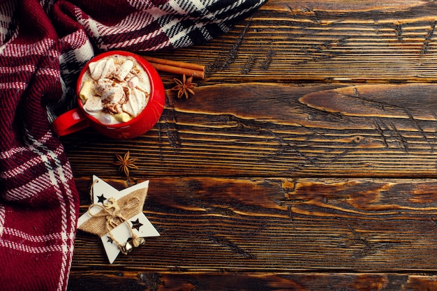 Bevanda invernale al caffè, cacao con panna montata e marshmallow in una tazza di ceramica rossa