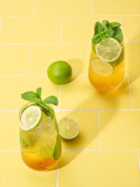 Bevanda lunga al rum Mojito o mojito vergine con menta fresca, succo di lime, zucchero di canna e soda su sfondo giallo