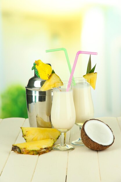 Bevanda Pina colada in bicchieri da cocktail e shaker di metallo su sfondo luminoso